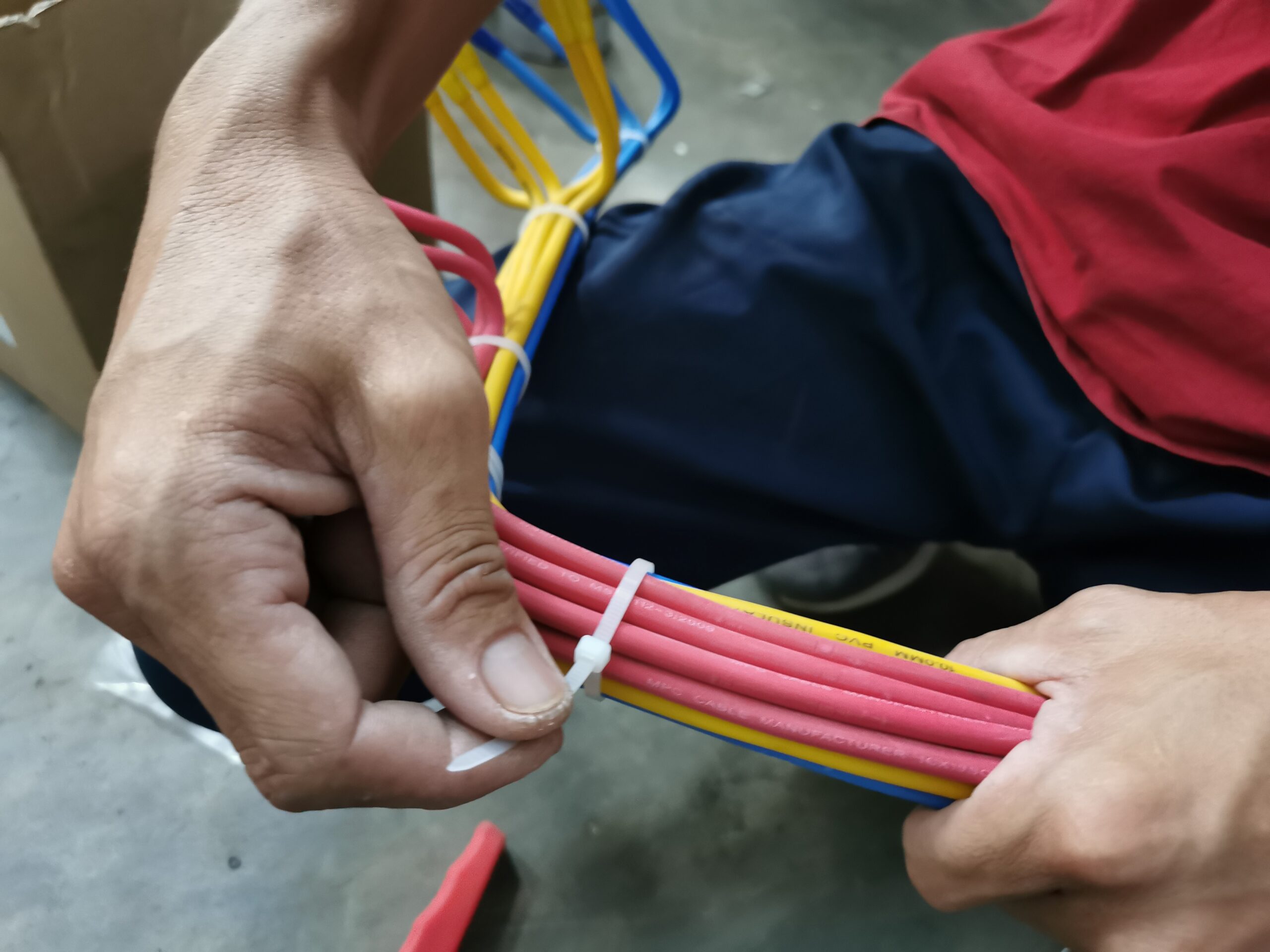 An electrical technician apply zip ties to a bundle of cables.